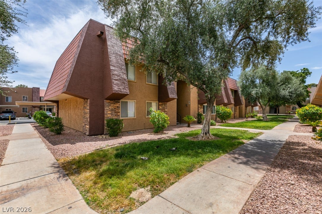 5240 Indian River Drive, #273, Las Vegas, NV 89103 Mature trees and paved walkways frame the exterior of this multi-level residential building.