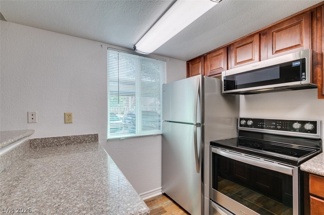 5240 Indian River Drive, #273, Las Vegas, NV 89103 Rich wood cabinets and durable stone countertops frame this functional kitchen space.