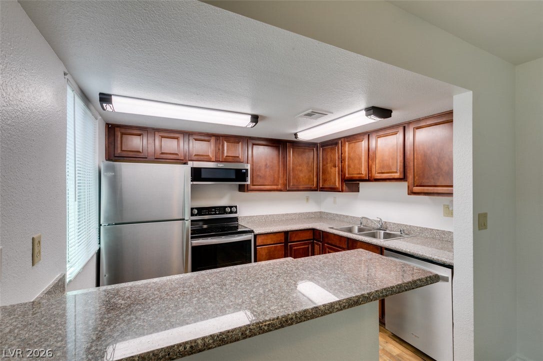 5240 Indian River Drive, #273, Las Vegas, NV 89103 Rich wood cabinetry contrasts beautifully with granite countertops in this functional kitchen layout.