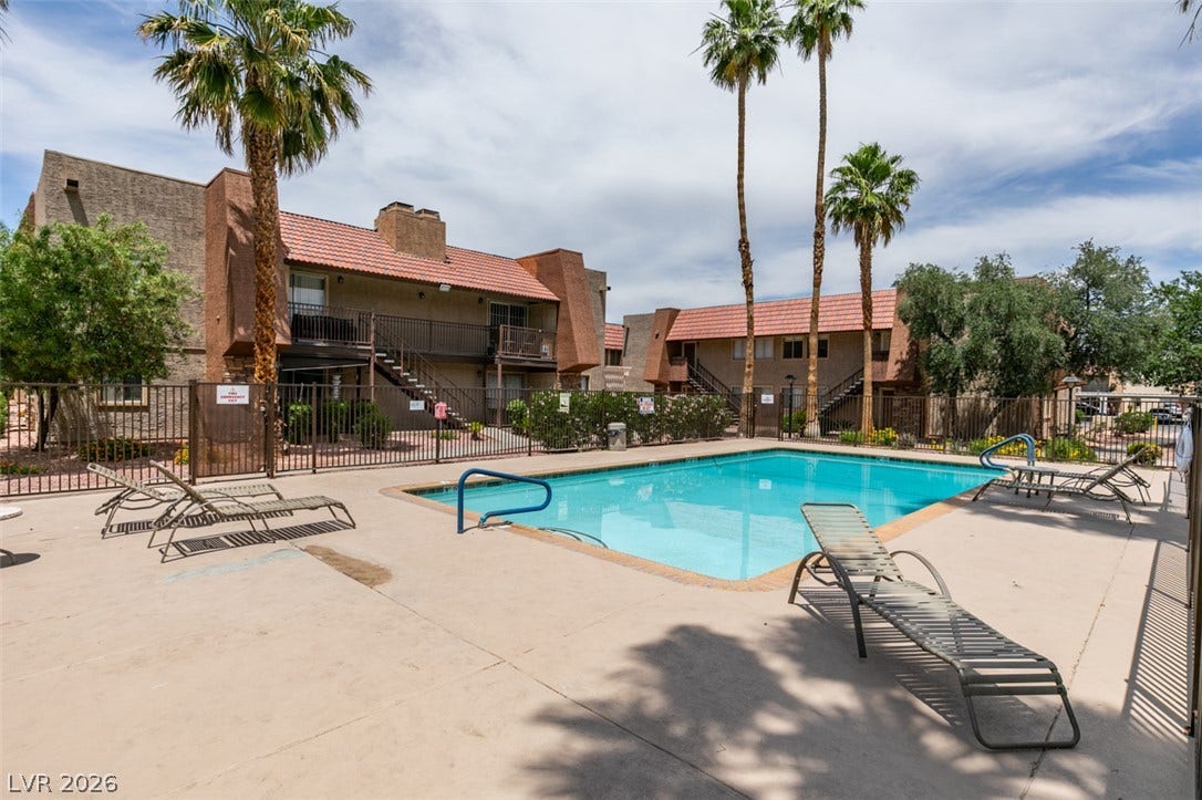 5240 Indian River Drive, #273, Las Vegas, NV 89103 A refreshing swimming pool sits enclosed by fencing near residential buildings and tall palm trees.