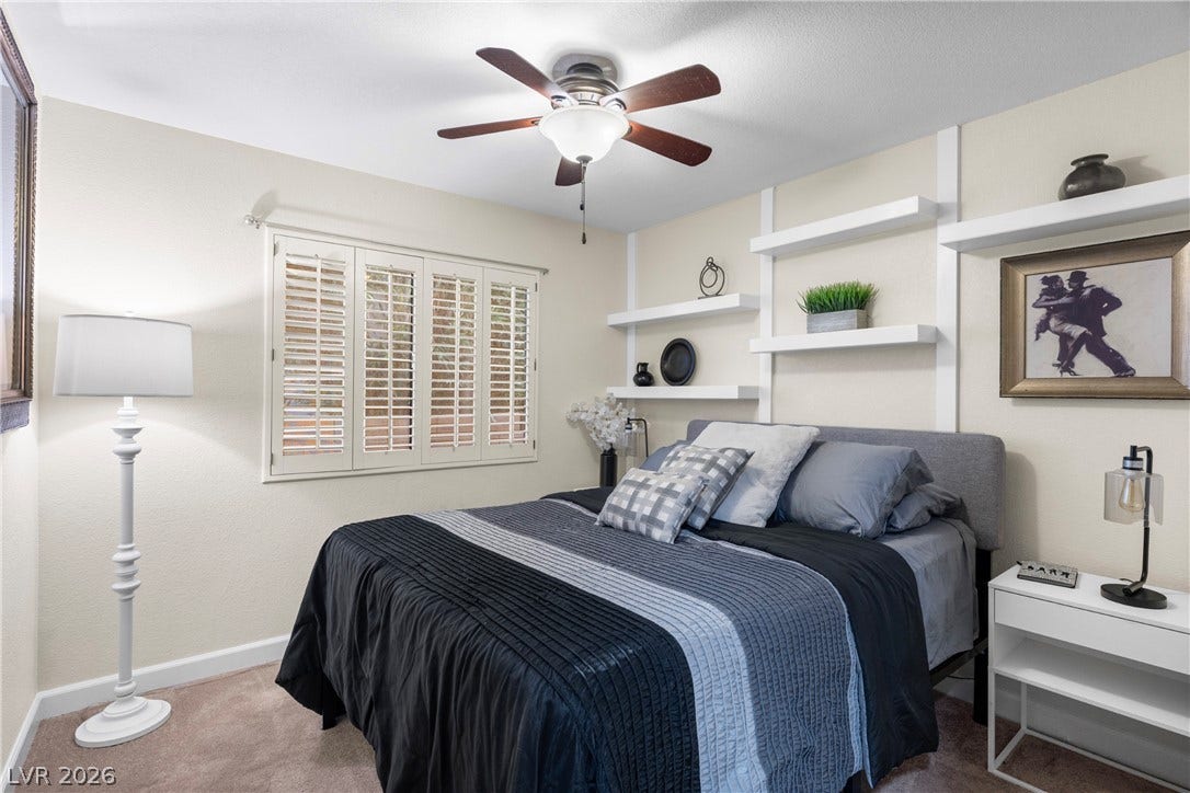 Plush carpeting anchors this inviting space featuring custom built-in wall shelving.