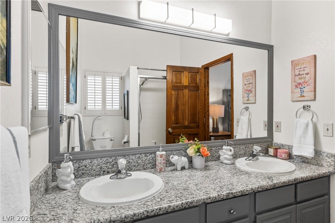 Polished granite countertops and dual sinks anchor this well-appointed bathroom space.