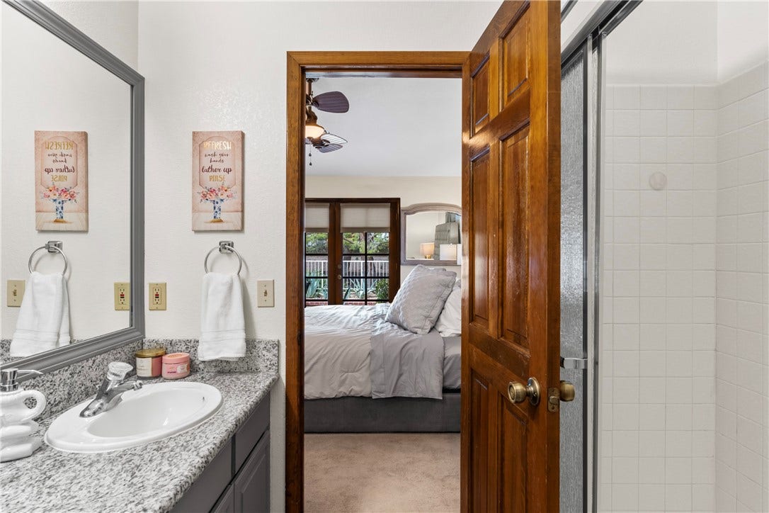 Granite counters and white tiling define this functional space connected directly to the bedroom.