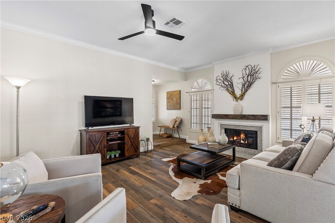Rich wood floors and a fireplace with a timber mantel anchor the welcoming living area.