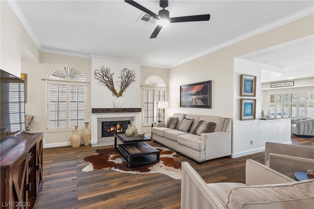 Rich wood-look flooring and a cozy fireplace anchor this open living area.