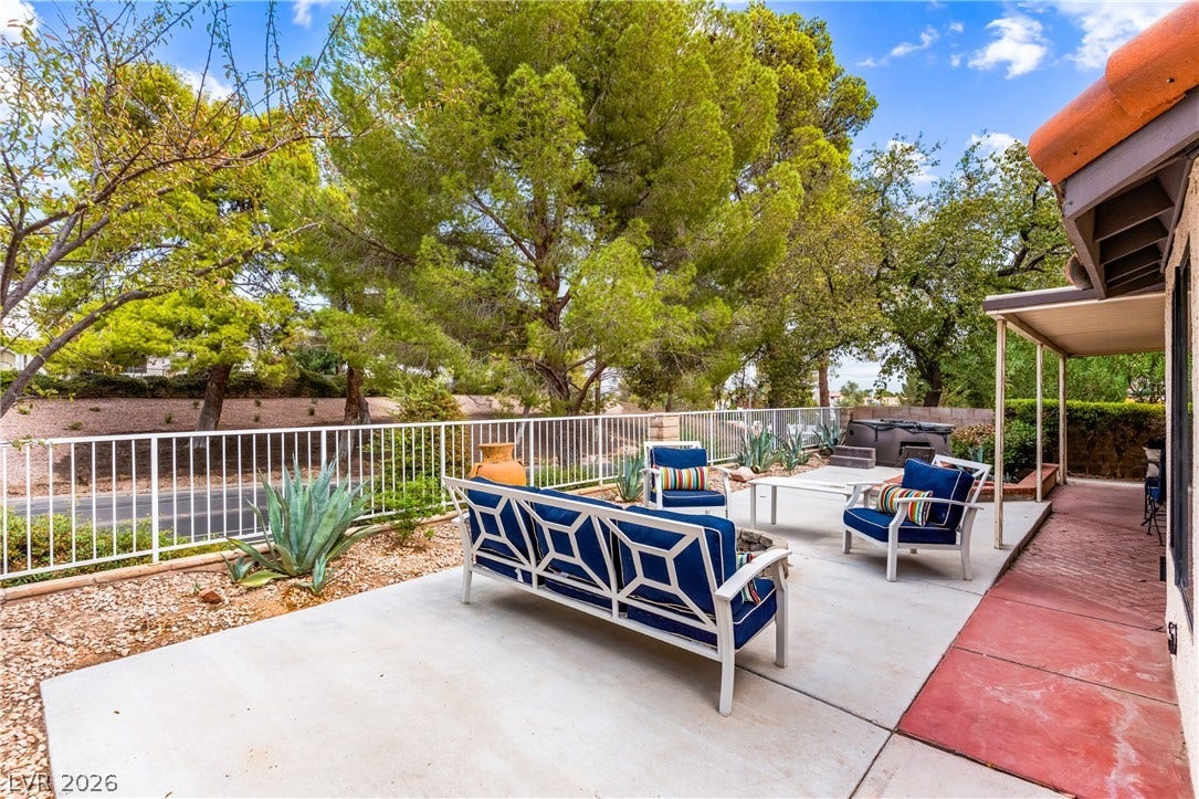 Mature trees frame a concrete patio area enclosed by secure perimeter fencing.