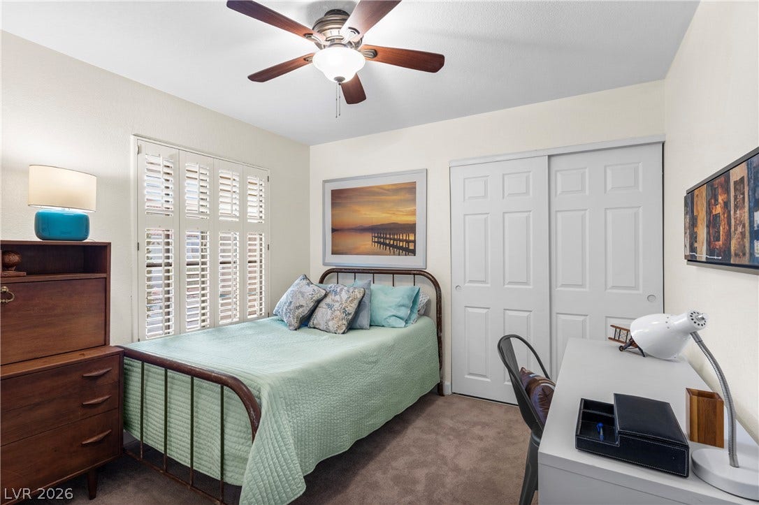 Plush carpet flooring and classic plantation shutters define this cozy secondary bedroom.