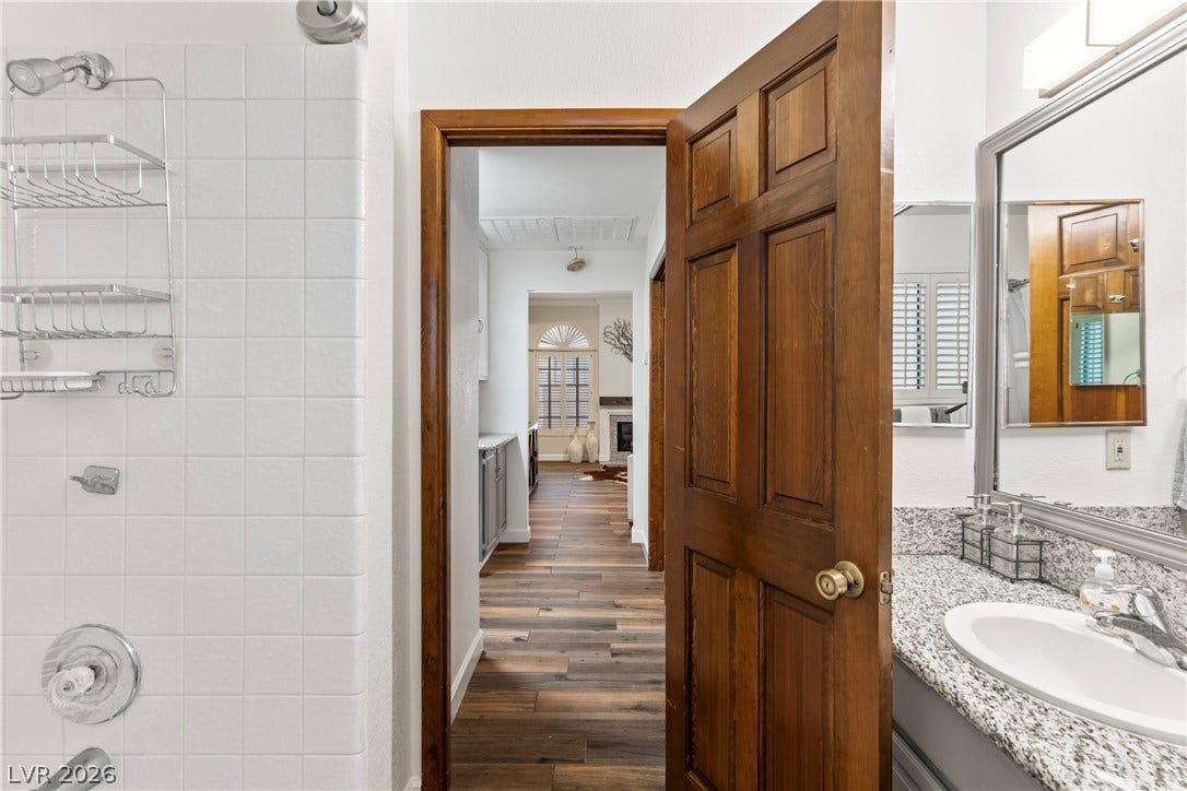 Rich wood trim frames the doorway leading from the vanity area toward the living spaces.