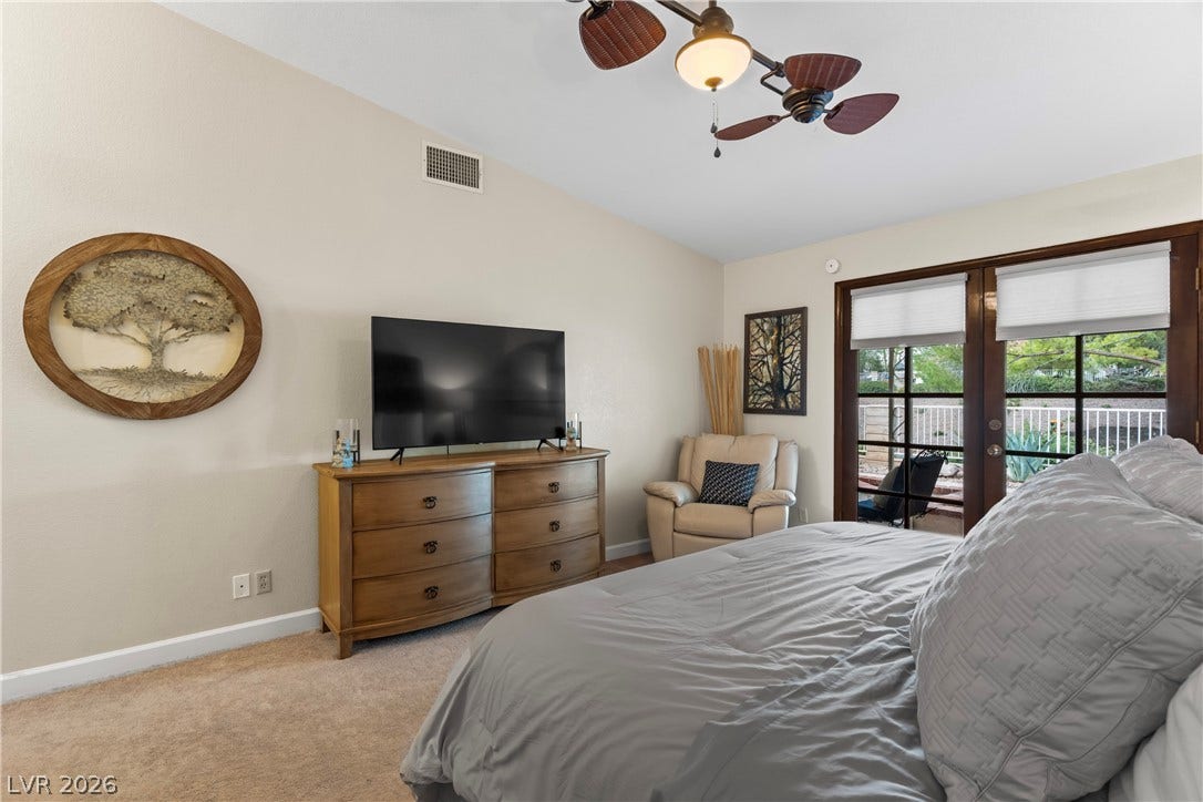 Double doors open directly to the outdoors from this plushly carpeted bedroom.