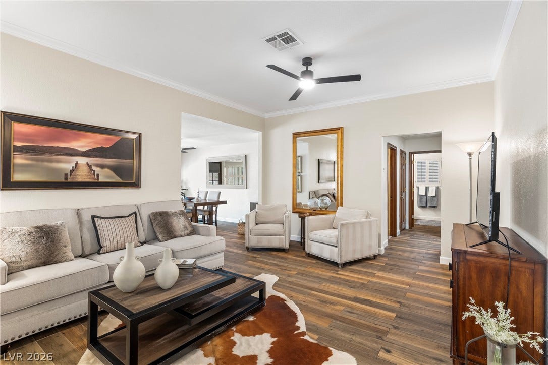 Rich wood-look flooring and crown molding define this open-concept main living space.