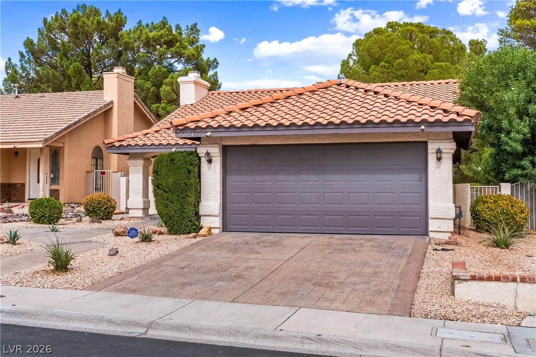 A spacious front-loading garage features a patterned concrete driveway beneath a classic tile roof.