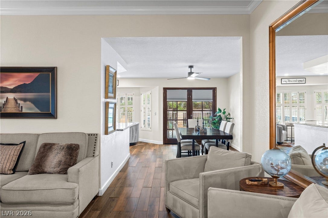 Warm wood flooring connects the comfortable living area to an adjacent dining room.