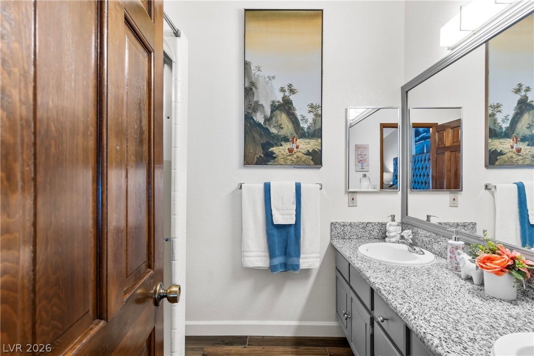 Polished stone counters and rich wood flooring elevate this modern bathroom design.