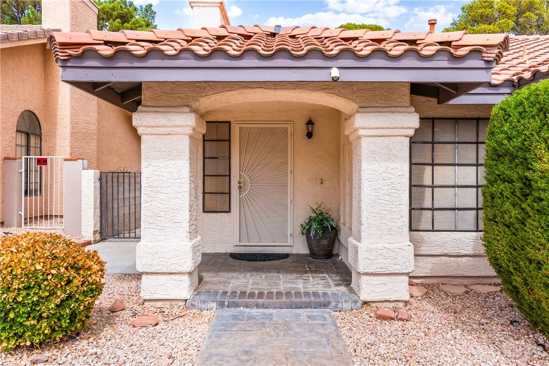 Stately stucco pillars frame a welcoming tiled entryway underneath a classic Spanish tile roof.