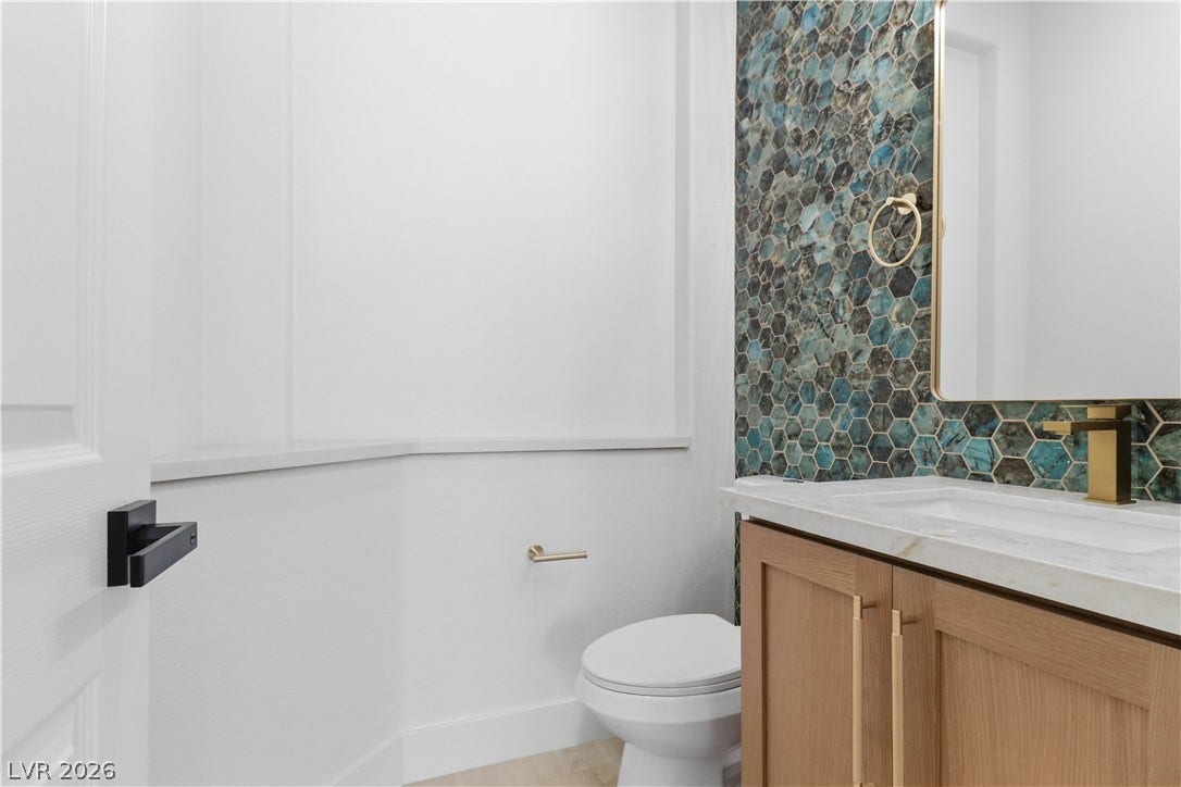5150 Villa Dante Avenue, Las Vegas, NV 89141 An elegant powder room features a custom wood vanity and a striking mosaic tile accent wall.