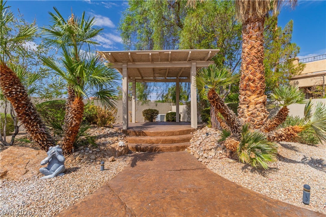 5150 Villa Dante Avenue, Las Vegas, NV 89141 Palm trees frame a stone path leading up to a shaded wooden pergola.