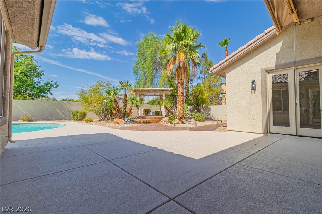5150 Villa Dante Avenue, Las Vegas, NV 89141 An expansive concrete patio overlooks the private backyard oasis featuring a pool and lush landscaping.