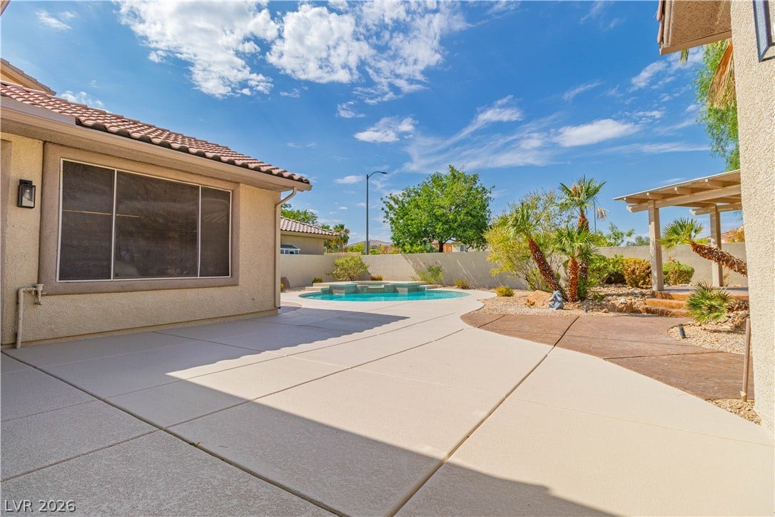 5150 Villa Dante Avenue, Las Vegas, NV 89141 An inviting backyard features a concrete patio alongside a private pool under clear blue skies.