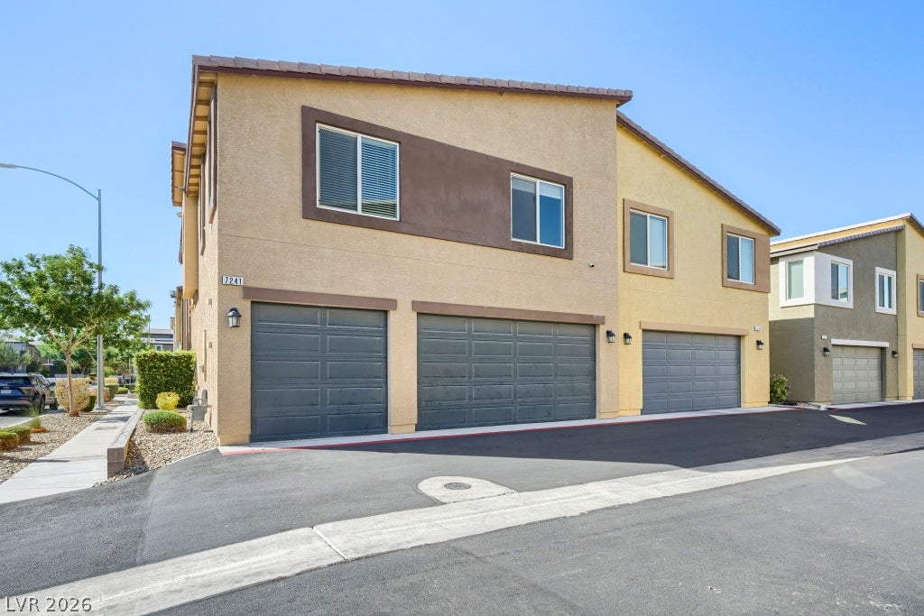 7241 Glistening Star Street, North Las Vegas, NV 89084 Multi-level modern townhomes display clean stucco exteriors and integrated garage parking along a paved driveway.