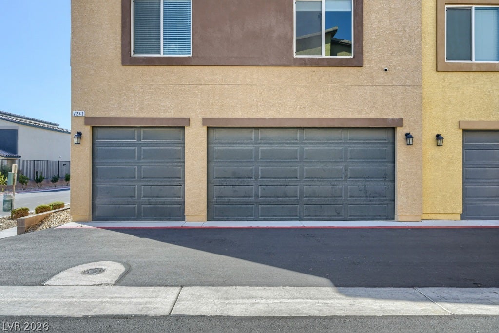 7241 Glistening Star Street, North Las Vegas, NV 89084 Multi-car garage entryways feature dark paneled doors beneath a stucco facade.