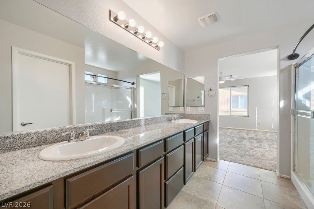 7241 Glistening Star Street, North Las Vegas, NV 89084 Polished stone counters and durable tile flooring define this spacious dual-vanity bathroom.