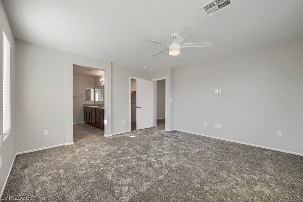 7241 Glistening Star Street, North Las Vegas, NV 89084 Plush carpeting anchors this spacious bedroom featuring direct access to an en-suite bath.