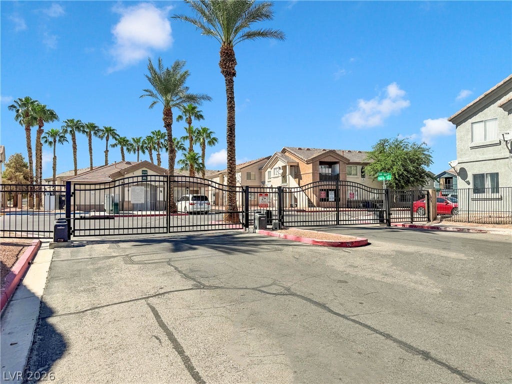 1520 Frank Aved Street, #201, Las Vegas, NV 89110 Secure gated access leads to this residential community under blue skies and towering palm trees.