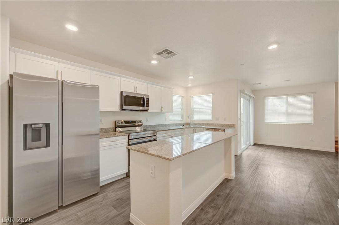 Granite countertops and clean white cabinetry highlight this open-concept culinary space.