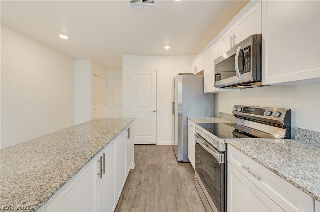 Polished granite countertops and classic shaker cabinetry define this modern, functional culinary space.