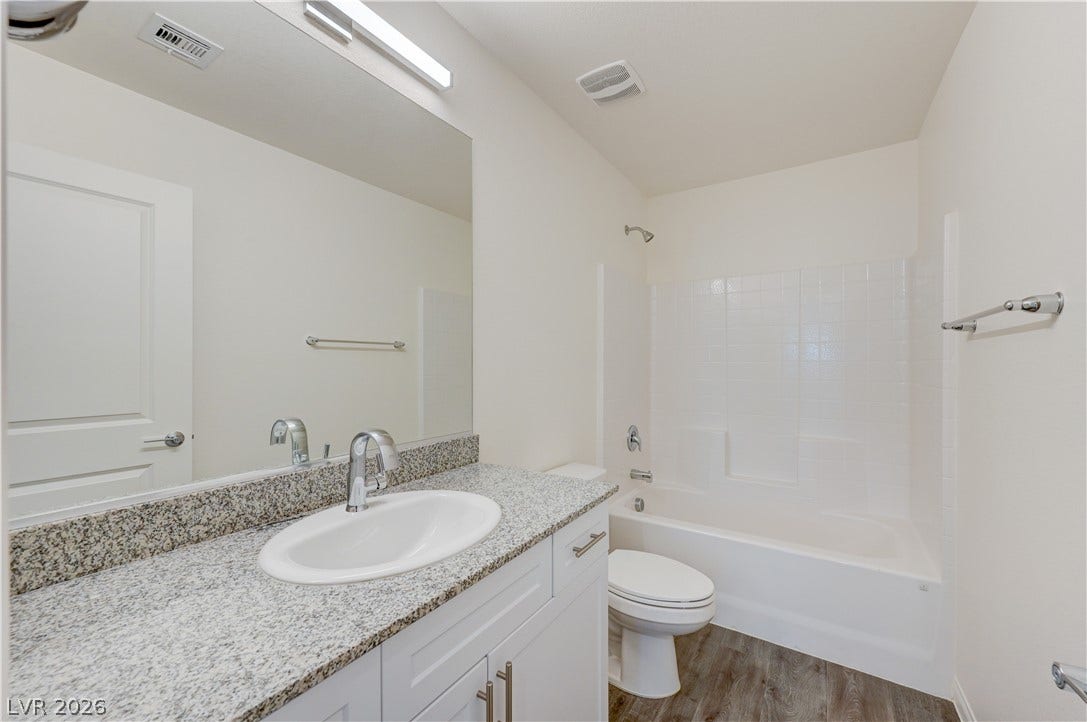 A polished granite vanity and classic tub shower surround highlight this functional bathroom space.