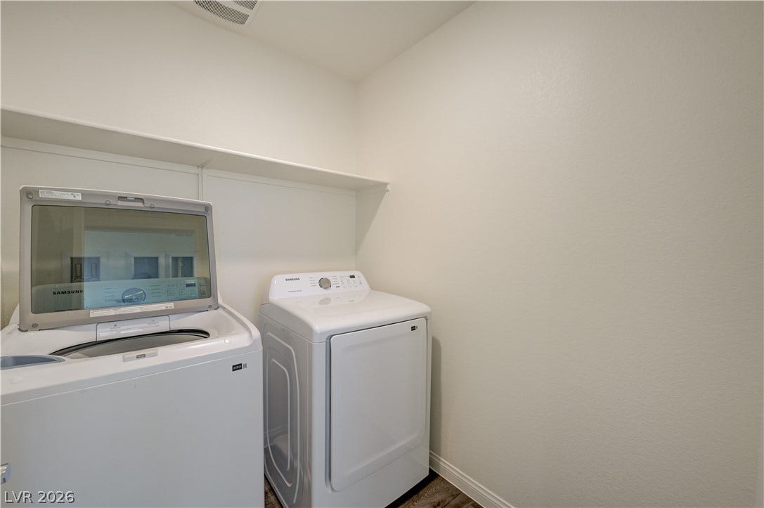Functional utility space includes built-in shelving above laundry appliances.