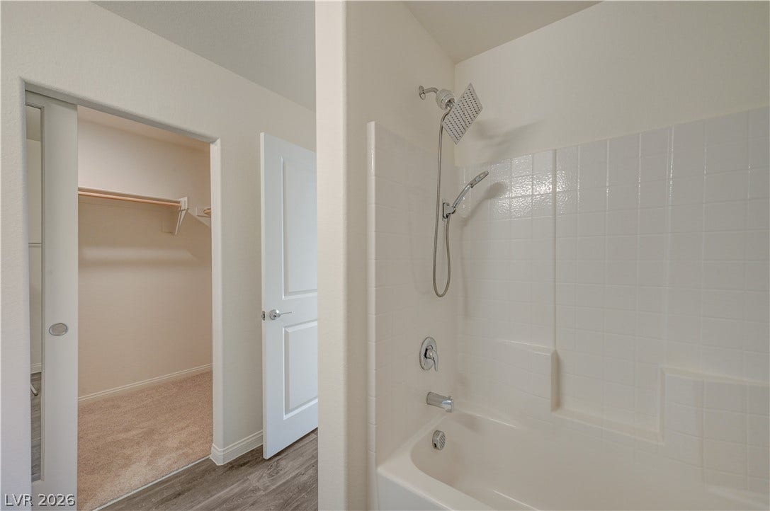 Tiled shower and tub combination connects seamlessly to a spacious walk-in closet.
