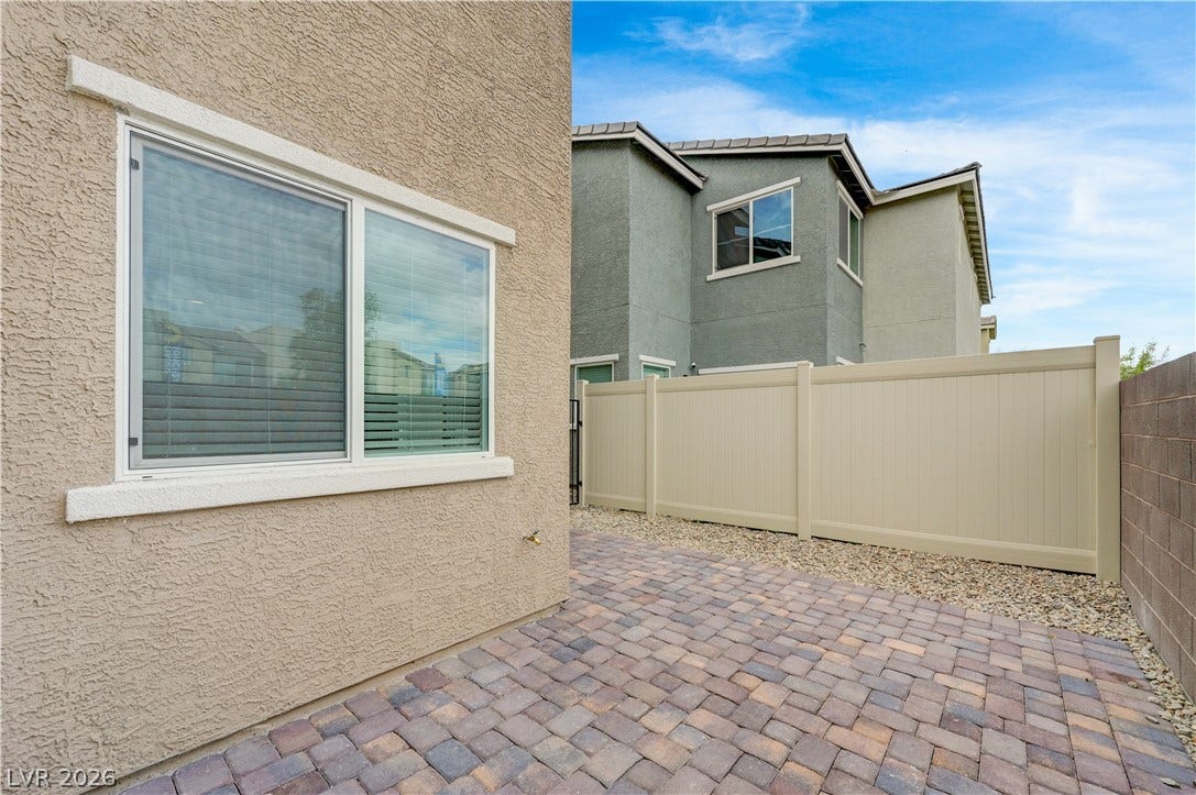 An inviting paved patio sits nestled alongside stucco walls under open blue skies.