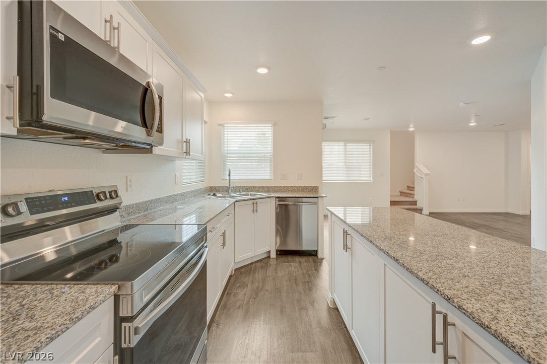 Polished granite countertops and modern appliances anchor this open-concept kitchen.