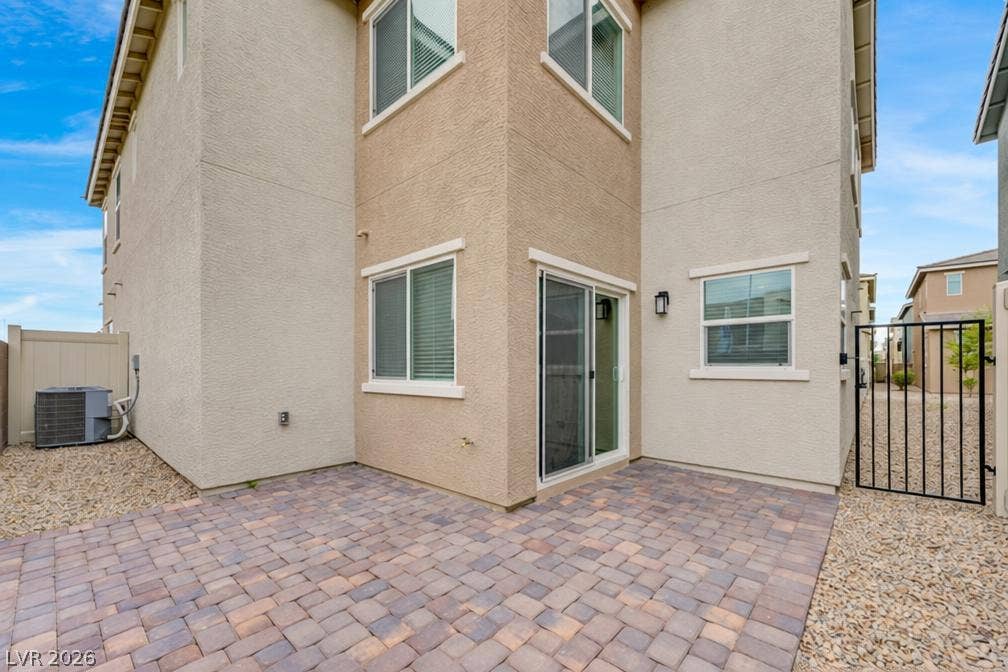 A paved brick patio borders the stucco exterior, offering a low-maintenance outdoor retreat.