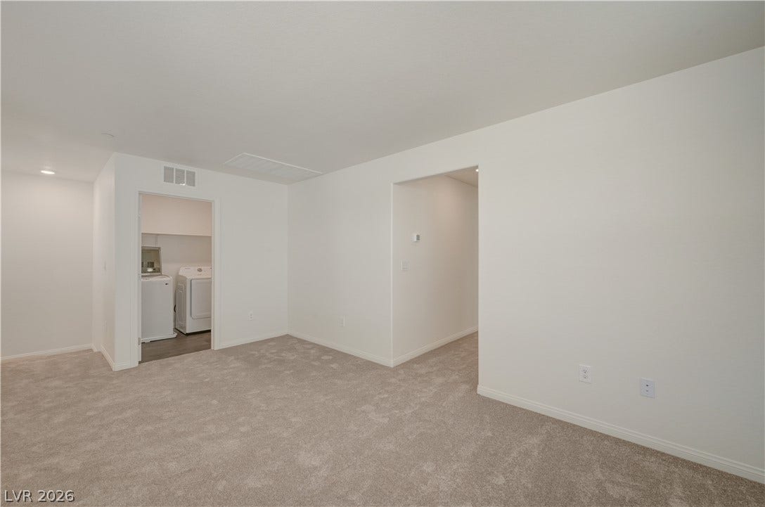 Plush carpeting anchors this versatile interior space featuring seamless transitions to an adjacent laundry area.