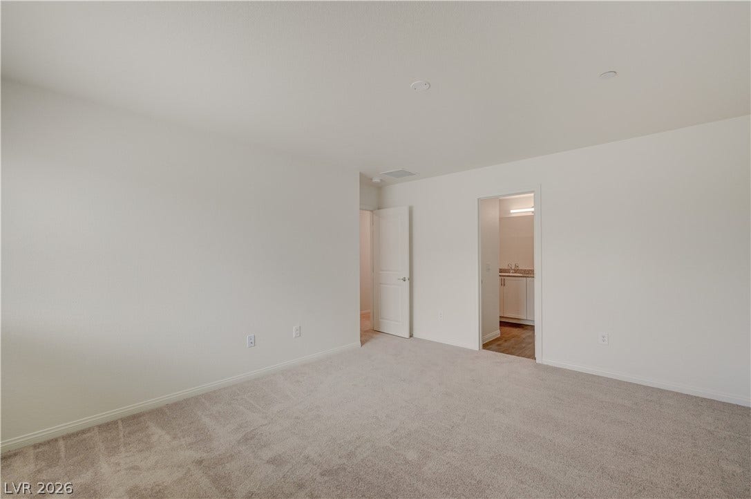 An open and versatile bedroom layout provides soft wall-to-wall carpeting and access to nearby spaces.