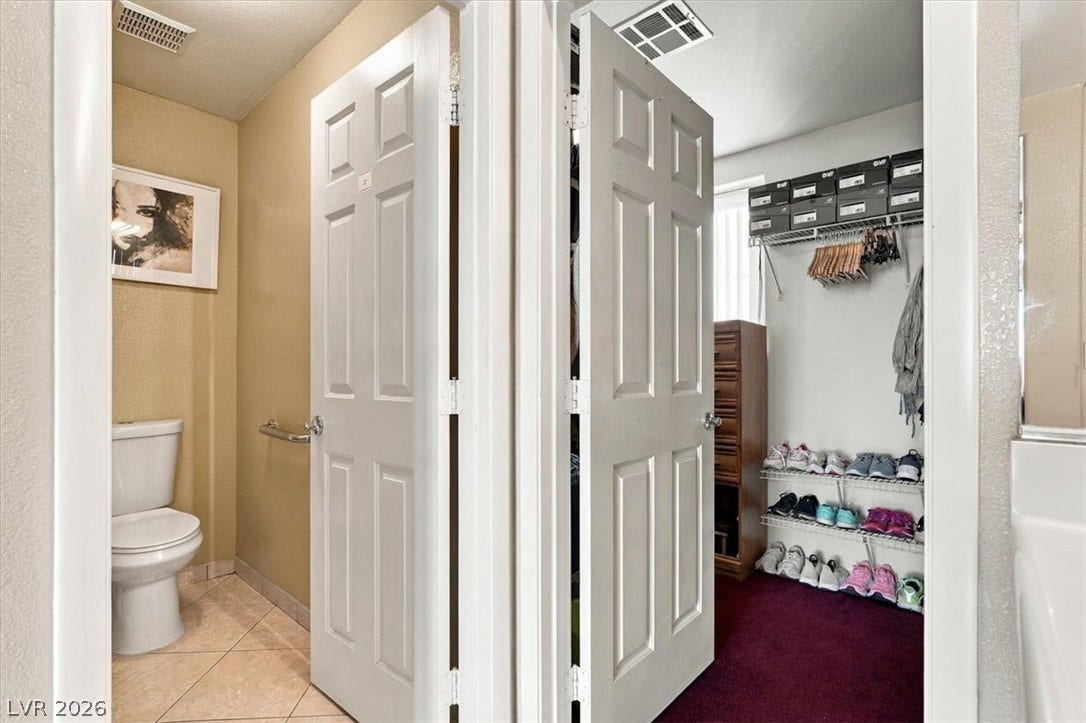 6329 Snow Cactus Street, North Las Vegas, NV 89031 Adjacent doorways lead to a powder room with tile flooring and a carpeted closet space.