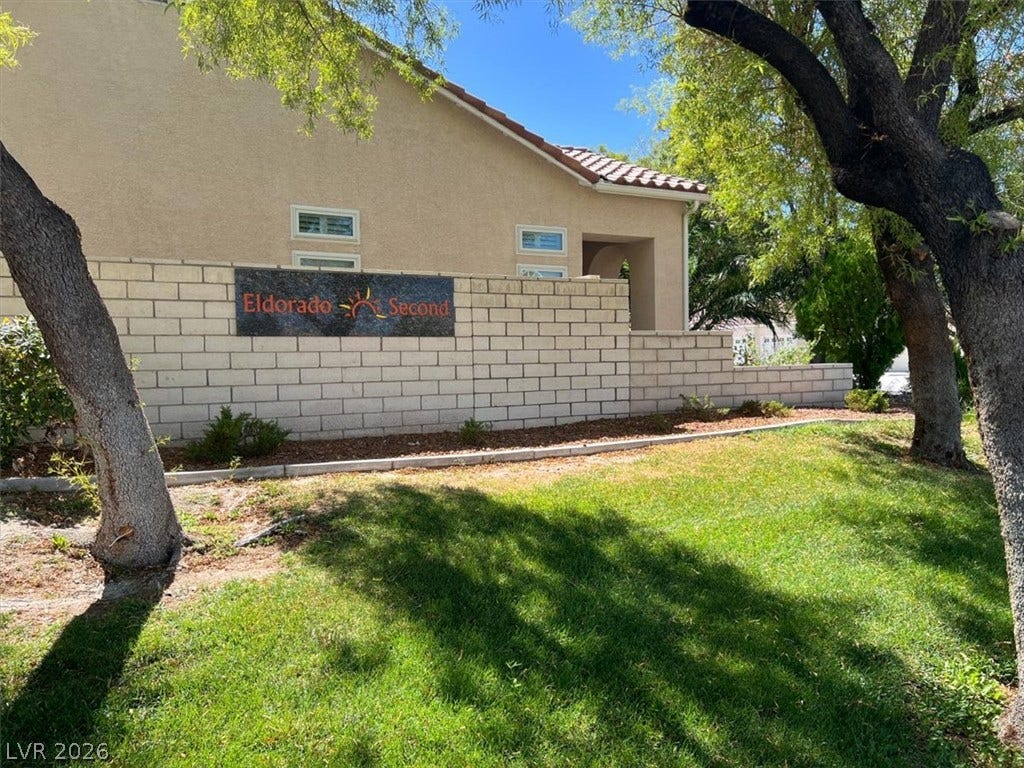 6329 Snow Cactus Street, North Las Vegas, NV 89031 Mature trees shade a neat lawn bordering a block privacy wall and stucco exterior.