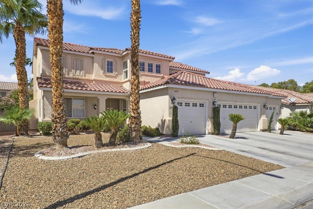 6329 Snow Cactus Street, North Las Vegas, NV 89031 Palm trees frame a classic tile roof and stucco facade under clear desert skies.