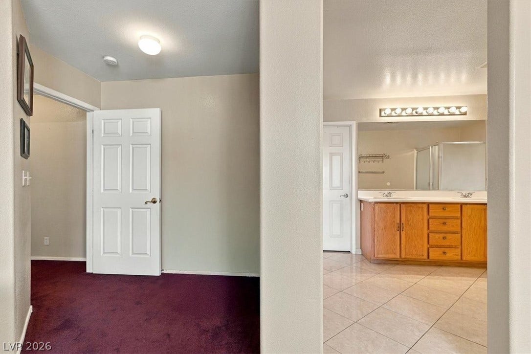 6329 Snow Cactus Street, North Las Vegas, NV 89031 A spacious carpeted dressing area connects seamlessly to an en suite bathroom with tile flooring.