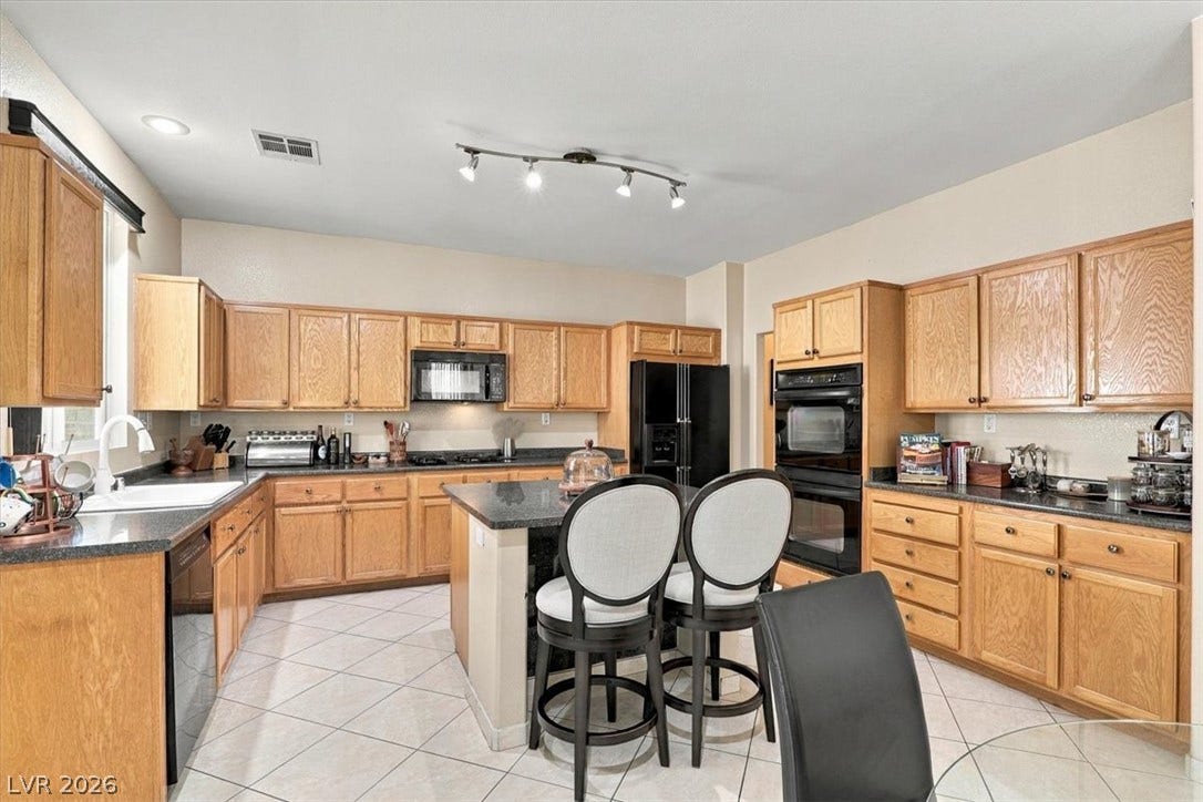 6329 Snow Cactus Street, North Las Vegas, NV 89031 Ample wooden cabinetry and dark stone countertops anchor this functional cooking space.