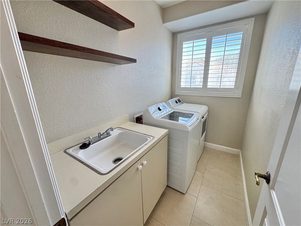 A functional workspace with built-in cabinetry, an integrated utility sink, and durable tile flooring.