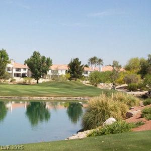 Lush fairways and a serene water hazard frame views of the surrounding neighborhood.