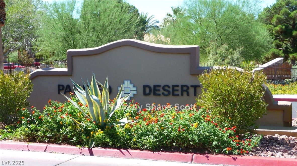 Lush desert landscaping surrounds the prominent community entrance sign.