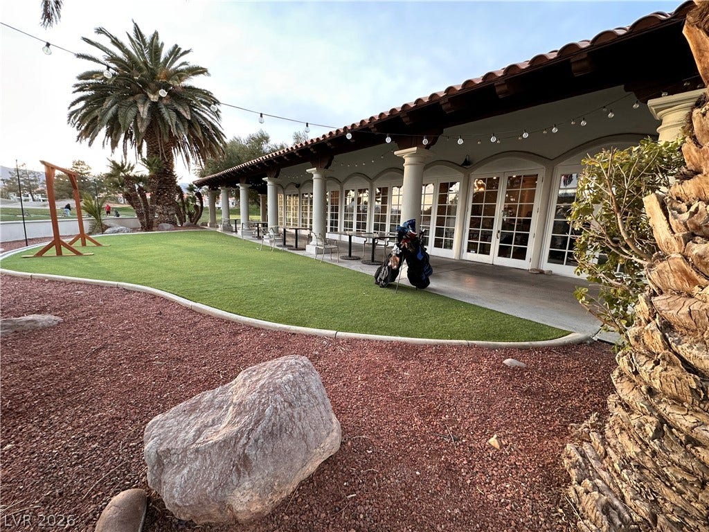 A spacious covered patio features classic columns alongside a manicured lawn area.