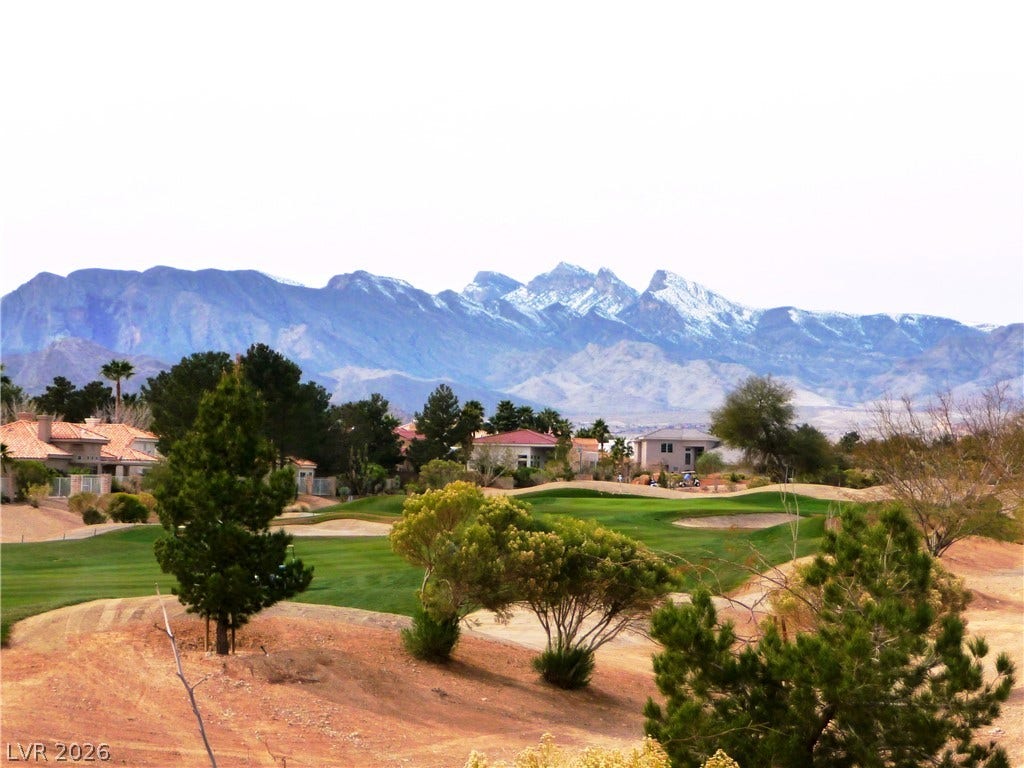 Dramatic mountain peaks provide a majestic backdrop to the manicured golf course greens.