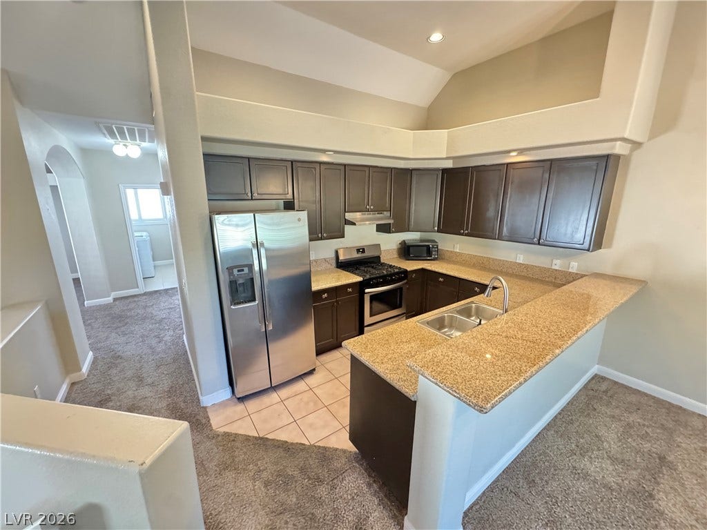 High ceilings look down upon a well-appointed kitchen outfitted with granite countertops.