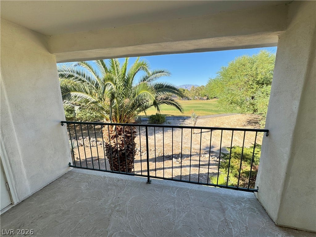 A private covered balcony frames scenic golf course and mountain views through mature palm trees.