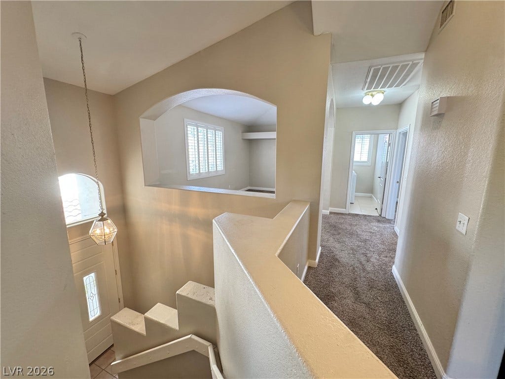 An open stairway landing connects distinct living areas under vaulted ceilings.